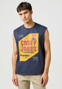 Marinblå ärmlös t-shirt med en stor gul och rosa grafik som står "CASEY JONES FOR WORKERS" och Wrangler-logotypen längst ner.