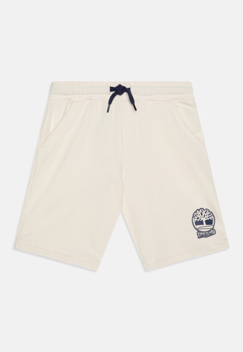 Pantalones cortos color crema confeccionados en material suave, con una cintura ajustable de cordón azul marino y bolsillos laterales. Un logotipo de Timberland en azul marino está en la pierna izquierda.