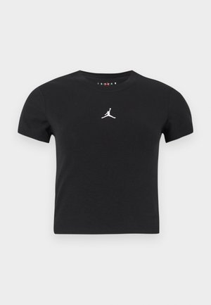 Černé krátké rukávy, zkrácený tričko s bílým logem Jumpman umístěným na středu hrudi na jednoduchém pozadí.