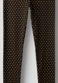 Brune leggings med en ribbet tekstur, med et mønster av små kremfargede polkadotter jevnt fordelt over hele stoffet.