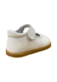 Zapato Mary Jane de cuero blanco con punta redonda, detalles perforados y una cinta de velcro, montado sobre una suela de goma marrón claro.
