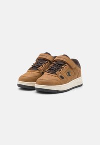 Zapatillas marrones con un upper de gamuza suave, acentos más oscuros, cordones color topo, detalles perforados y una media suela blanca, que presenta un logo en el costado.