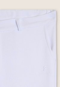 Pantalones deportivos blancos hechos de tela suave, con una cintura elástica, bolsillos laterales y el logo bordado "FREDDY" en el frente.