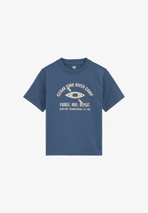 Plava majica kratkih rukava s bež natpisom "Cedar Fork River Camp" i "Paddle. Hike. Repeat." oko grafike kajaka i vesla.