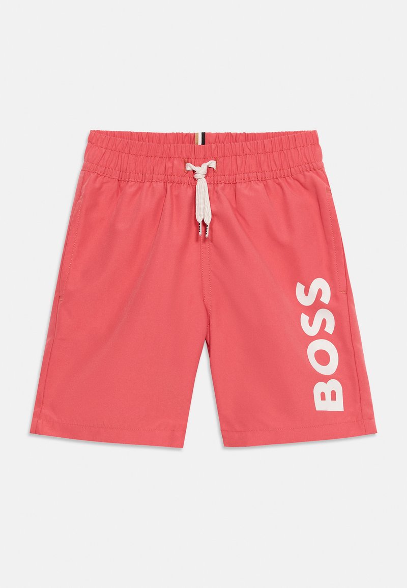 Shorts à taille élastique corail rose avec cordon de serrage blanc et grand logo "BOSS" blanc imprimé verticalement sur la jambe droite.