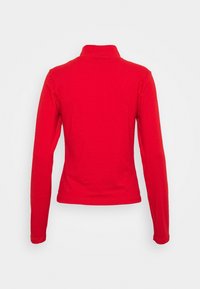 Röd långärmad topp med hög krage, åtsittande design och slät yta. Bakifrån syns rena linjer och inga synliga detaljer.