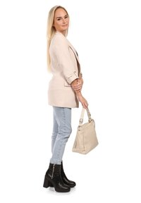 Beige blazer met opgerolde mouwen, lichtblauwe jeans en zwarte enkelboots. Houdt een lichtbeige schoudertas vast. Eenvoudig ontwerp, gladde textuur.
