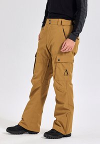 Bruine waterdichte cargobroek met een losse pasvorm, voorzien van meerdere zakken, een logo op de bovenbeen en een beveiligde tailleband.