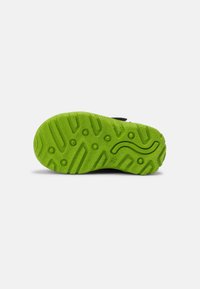 Suola della scarpa in gomma verde brillante con motivi testurizzati, tra cui scanalature e design circolari, che garantiscono aderenza e durata.
