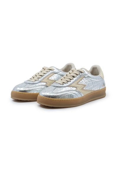Coppia di sneakers basse con tomaia argentata texturizzata, lacci e dettagli beige, e suole in gomma marrone chiaro su sfondo bianco.