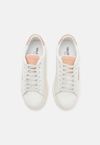 Bílé kožené tenisky se světlými růžovými detaily, kulatými tkaničkami, polstrovaným límcem a texturovaným povrchem, zobrazené shora.