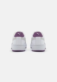 Sneakers bianche con accenti viola sul tallone, tomaia in pelle liscia, suola in gomma e cuciture a contrasto sui lati. Logo PUMA sul retro.