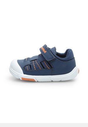 Încălțăminte sport de culoare albastru marin, cu talpă albă, accente portocalii, curea Velcro, panouri laterale din plasă și capac din cauciuc pentru degete.