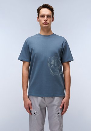 T-shirt en coton bleu à col rond et manches courtes. Présente un impression graphique tonale sur le côté gauche. Assorti avec un pantalon cargo gris clair.
