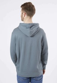 Sweat-shirt à capuche en bleu pastel, fabriqué en tissu doux. Doté d'une poche kangourou et de poignets et d'un ourlet côtelés pour un ajustement confortable.