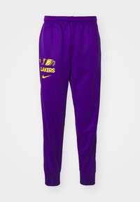 Calças atléticas roxas feitas de um tecido liso e leve, apresentando um logo amarelo dos "Lakers" e um pequeno swoosh da Nike na frente.