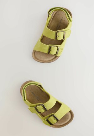 Sandales en daim vert avec deux boucles réglables, design à bout ouvert et semelle intérieure rembourrée marron, présentées de dessus.