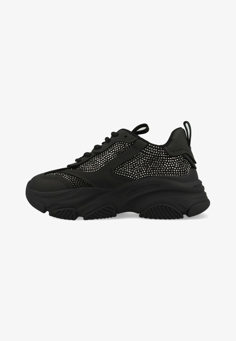 Black sneakers with a textured mesh panel, featuring a thick rubber sole, round toe, and laces. Small pull tab at the rear.