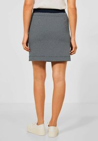 Marinblå mönstrad kjol med en slät yta och smal passform, med ett brett midjeband. Bärs med vita plattformssneakers.