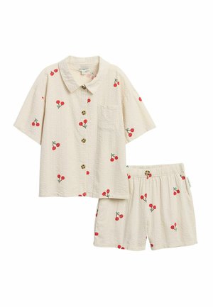 Hellbeiges kurzärmeliges Hemd mit Knöpfen und elastischen Taillen-Shorts mit roten Kirschmotiven, die über den Stoff verteilt sind.