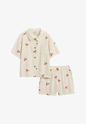 Hellbeiges kurzärmeliges Hemd mit Knöpfen und elastischen Taillen-Shorts mit roten Kirschmotiven, die über den Stoff verteilt sind.