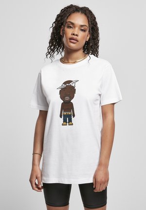 T-shirt en coton blanc avec un graphisme de dessin animé représentant un personnage à la peau marron avec un bandana, portant un pantalon bleu et des chaussures jaunes.