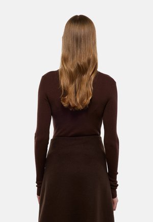 Top marron à manches longues côtelé, associé à une jupe marron foncé, présentant une silhouette ajustée et une texture lisse, vue de dos.