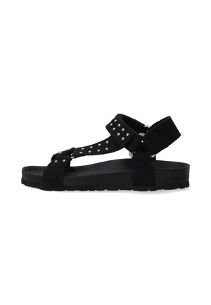 Sort ruskindsandal med nitter, justerbar ankelrem og flad gummisål. Simpelt design med åben tå.