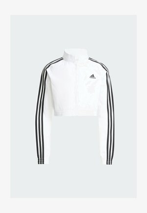 Bijela kratka Adidas trenirka s punim patentnim zatvaračem, crnim tri prugama duž rukava i Adidasovim logotipom na lijevoj strani prsa.