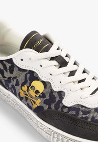 Zapatilla que presenta una parte superior de tela con un patrón de camuflaje azul marino, acentos de cuero blanco, diseño de calavera dorada y suela de goma gris texturizada.