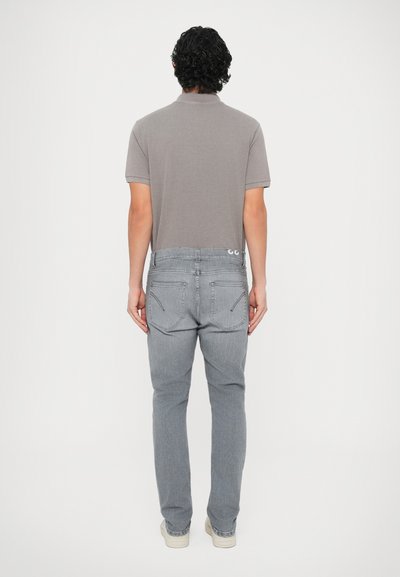 Γκρι κοντομάνικο πουκάμισο με απλό γιακά, σε συνδυασμό με ανοιχτό γκρι τζιν παντελόνι που διαθέτει πίσω τσέπες και διακριτικές ραφές.