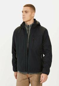 Veste softshell noire pour homme avec capuche, poches zippées et une couche intérieure texturée grise, dotée d'un ourlet ajustable et d'une marque discrète.