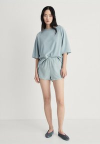 Lichtblauw, zacht van textuur, oversized t-shirt gecombineerd met bijpassende shorts. De outfit heeft een elastische tailleband en een casual pasvorm.