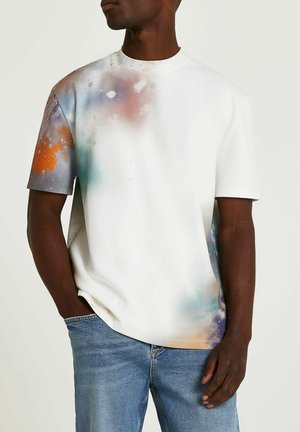 Korte mouwen, wit t-shirt met een kleurrijk, abstract spetterpatroon in oranje, blauw en paars. Soepele textuur, relaxte pasvorm.