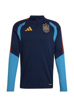 Tmavomodré športové tričko s dlhým rukávom, svetlomodré manžety na rukávoch, červené a žlté pruhy na pleciach, žlté logo Adidas a erb španielskej futbalovej reprezentácie na hrudi.