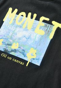 Schwarzes T-Shirt mit einem bunten Druck von Monets Gemälde, versehen mit dem Text "MONET" und "Öl auf Leinwand" in Gelb. Weicher Stoff.