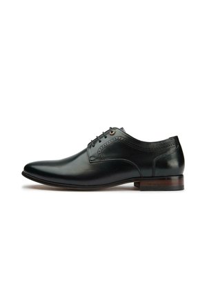 Black leather oxford shoe with a pointed toe, five lacing holes, stitched detailing on the upper, and a wooden heel accent.