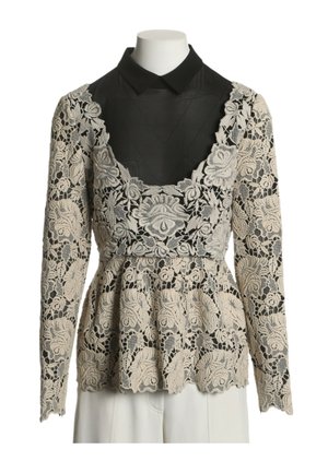 Haut en dentelle florale beige à manches longues sur chemise noire à col, taille ajustée, ourlet festonné, présenté sur un torse de mannequin blanc.
