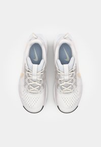 Baskets blanches avec une tige en mesh respirant, des lacets gris clair et des accents beige subtils ; bout arrondi et semelles rembourrées.