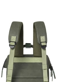 Grüner Rucksack mit gepolsterten Schulterriemen, strukturierten Materialien, verstellbaren Clips und mehreren Befestigungspunkten für Zubehör.