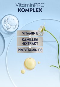 VitaminPRO KOMPLEX on light blue background. Features a droplet of pale yellow serum, a daisy flower, and text highlighting active ingredients.