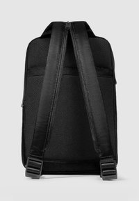 Zwarte rugzak gemaakt van gestructureerd nylon, voorzien van twee verstelbare riemen, een ritssluiting aan de bovenkant en een glad rugpaneel met minimale accenten.