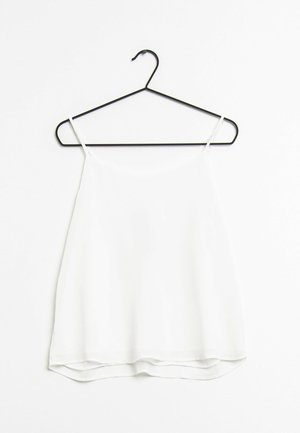 Haut blanc sans manches accroché à un crochet noir. Fabriqué en tissu léger avec une texture lisse et un ourlet arrondi.