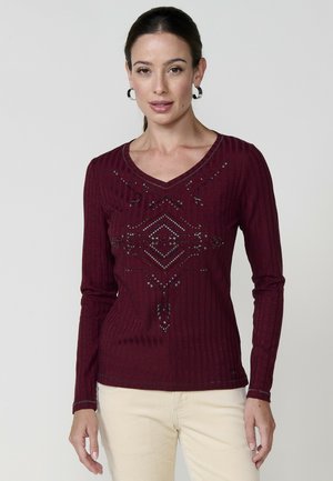 Bordo dugih rukava s rebrastom teksturom, V-izrezom i dekorativnim beaded uzorcima na prednjoj strani. Prilagođen kroj.