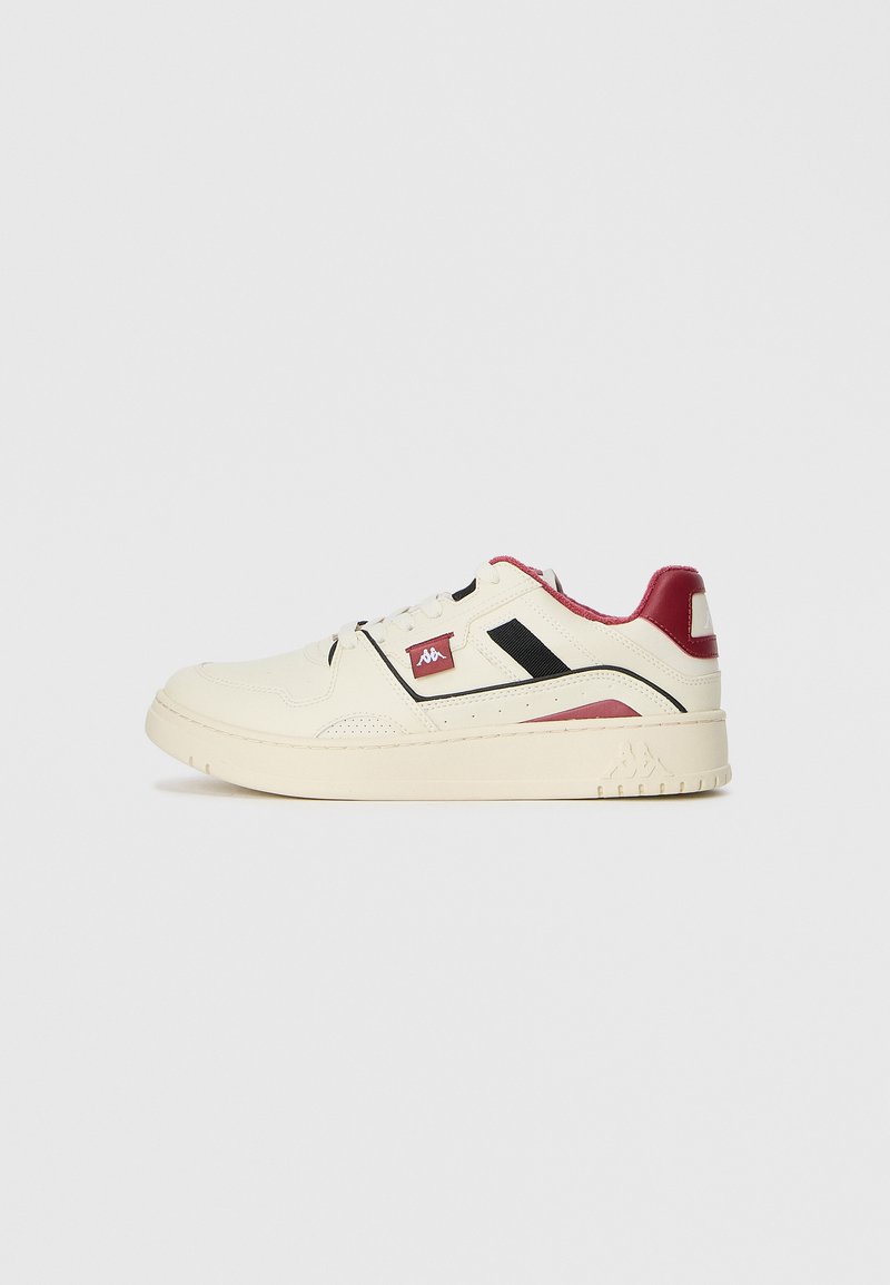 Cremfarbene Sneaker mit schwarzen und roten Akzenten, strukturiertes Lederobermaterial, Schnürdesign und flache Sohle mit einem Logo an der Seite.