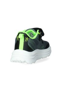 Scarpa sportiva nera con tomaia testurizzata e accenti verde neon, dotata di una fascia in Velcro e di una suola bianca con battistrada.