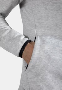 Lys grå hettegenser med teksturert stoff, med svart mansjettaksent og hånd i lommen for detaljer, med kengurulomme-design.