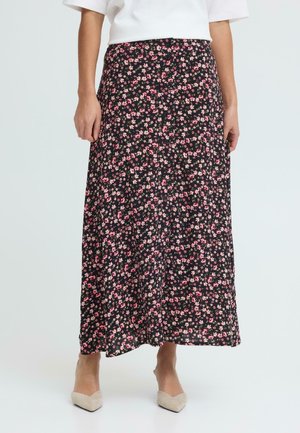 Jupe midi noire à petits imprimés floraux roses et blancs, portée avec un haut blanc et des talons pointus beige, vue de la taille aux pieds.