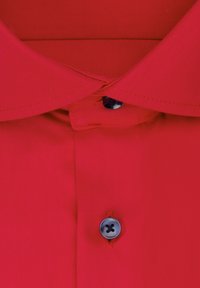 Chemise rouge avec un col classique, texture lisse et un bouton bleu foncé près du col. Le tissu semble sans plis.