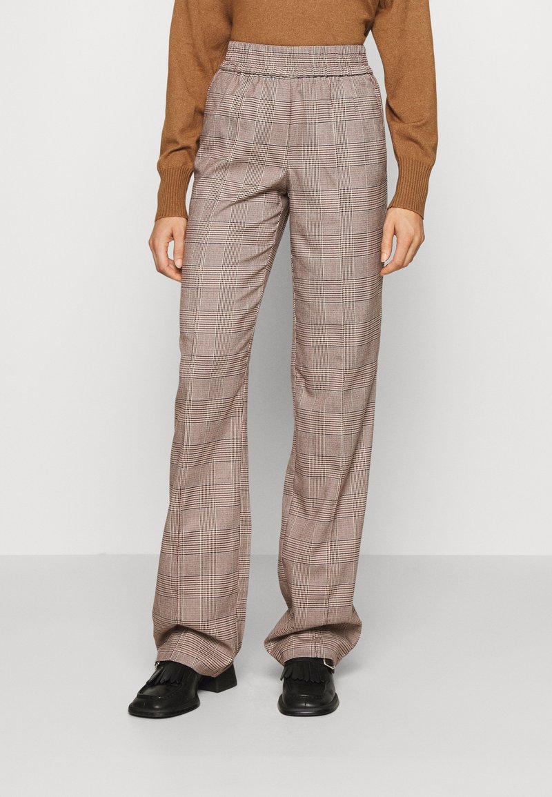 Plaid trousers in brown and cream, featuring an elastic waistband, wide-leg design, and side pockets. Worn with black footwear.